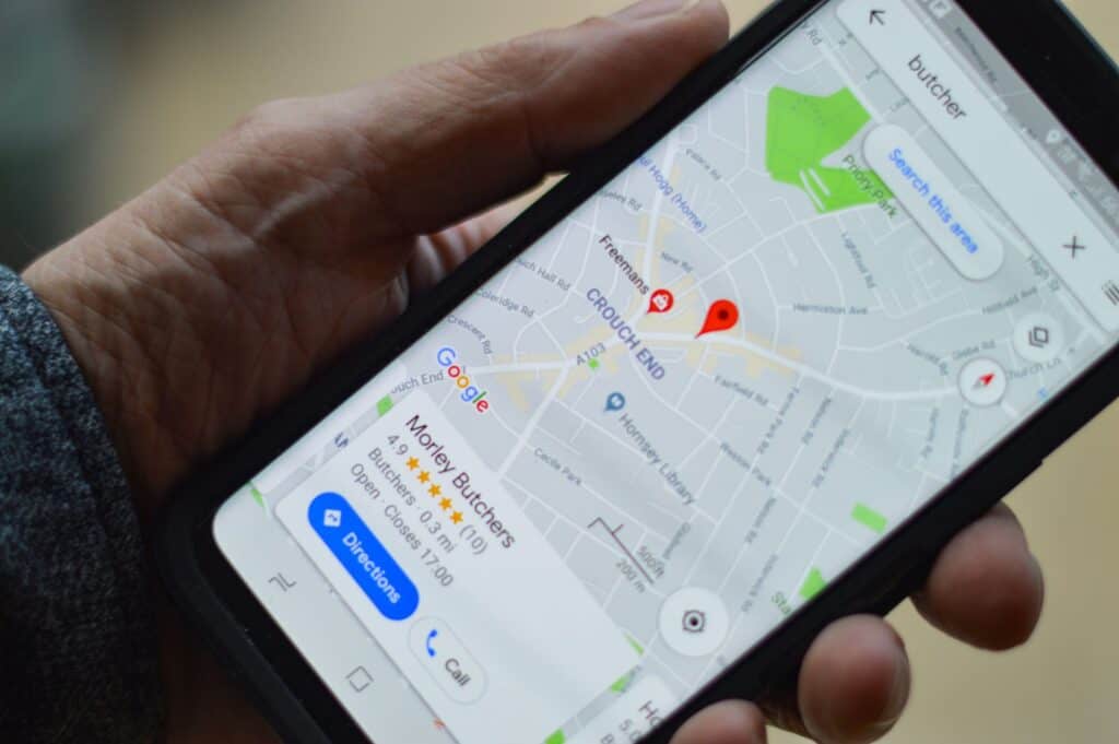 A person holding a cell phone with Google Maps displaying reviews.