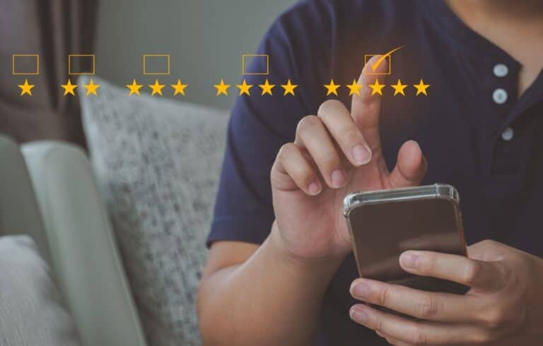 A business man using a smartphone with five stars on it.
