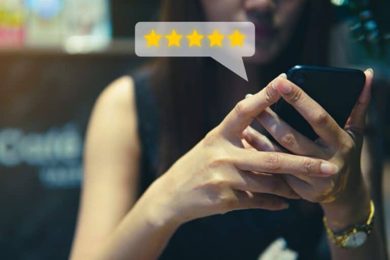 A businesswoman using a smartphone with a five star rating.