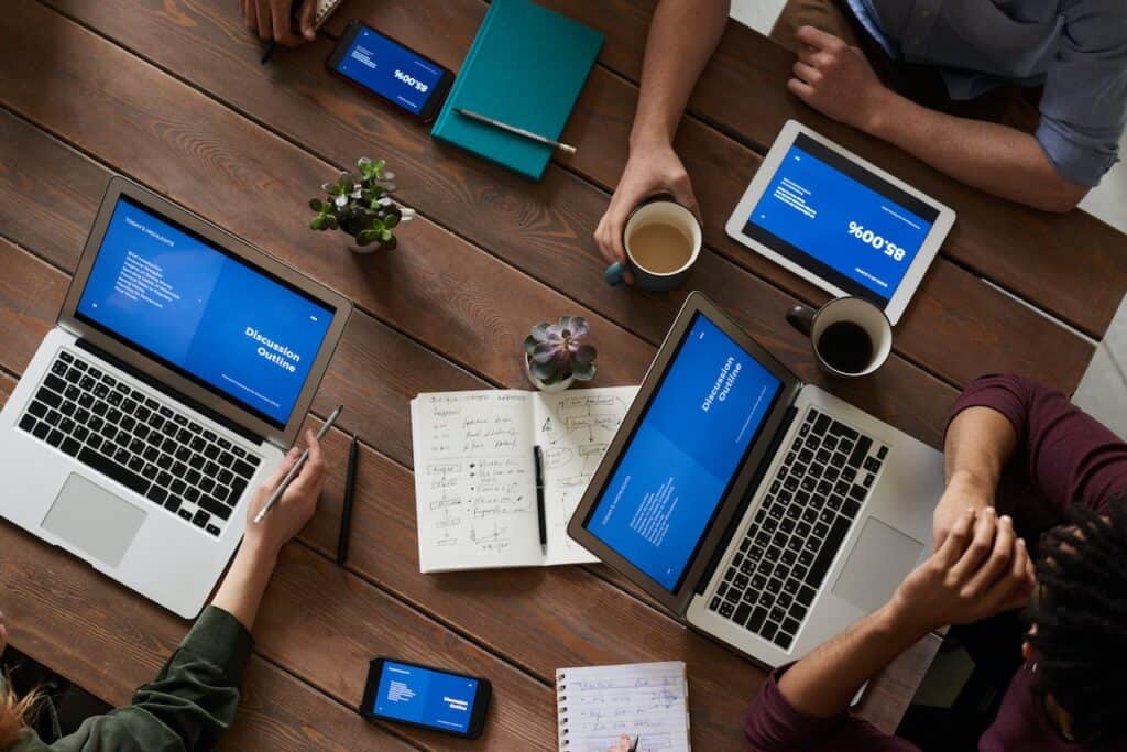 A group of people at a table using laptops to post Zenreviews or Yelp comments.