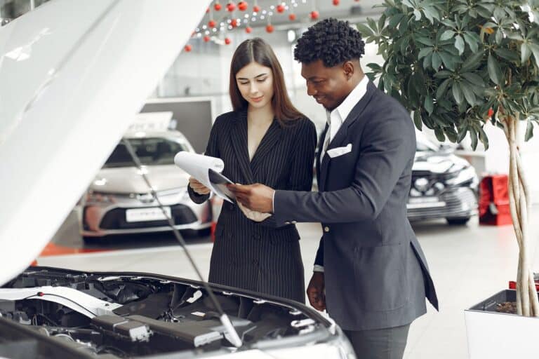 Two business people examining a car in a showroom to improve subject lines conversion.