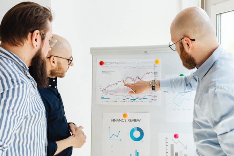 A group of business people analyzing graphs displaying zenreviews and customer feedback on a whiteboard.