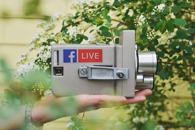 A person holding a camera with the word live on it.
