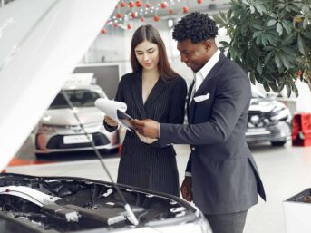 Two business people examining a car in a showroom to improve subject lines conversion.